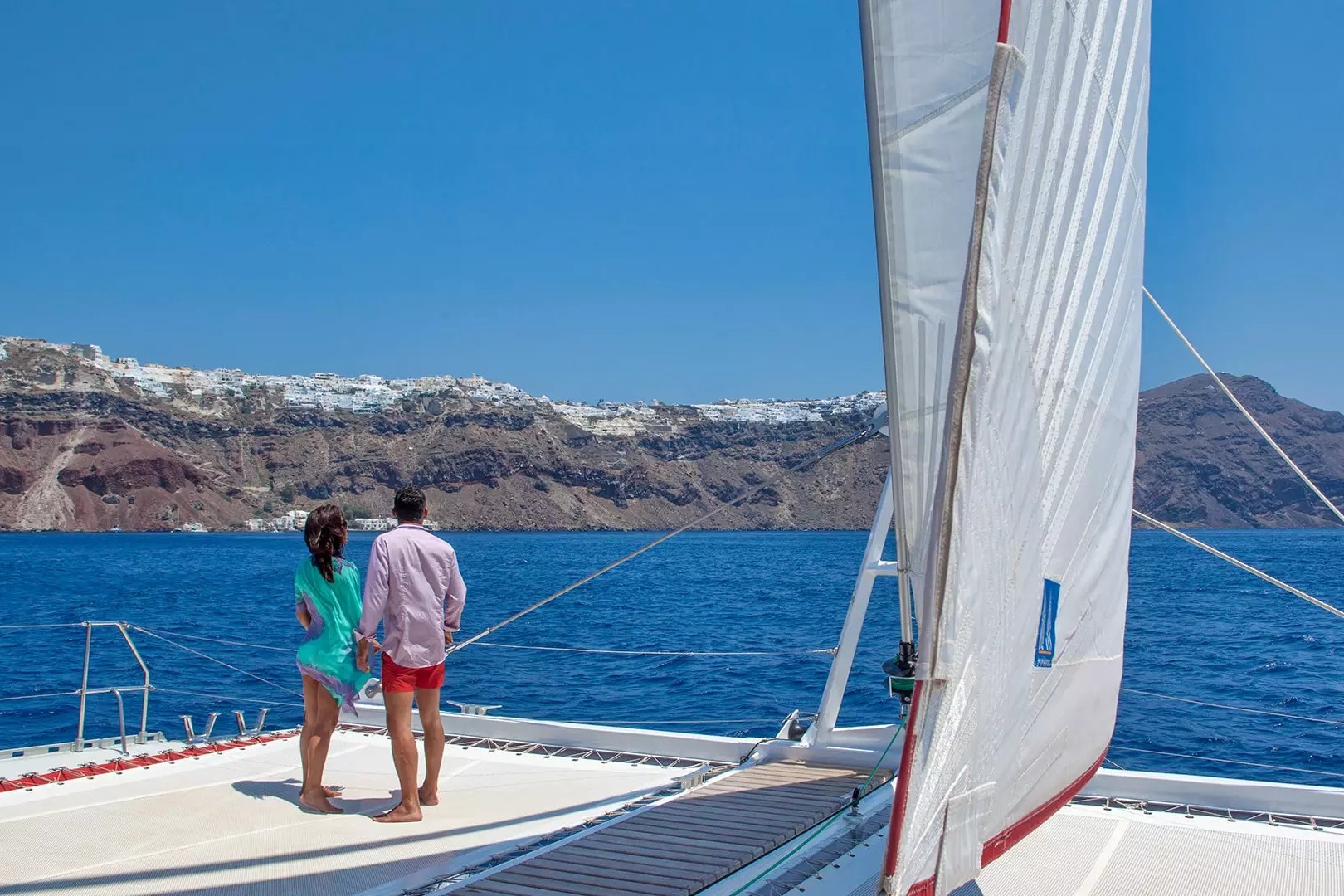 Passeio de barco em Santorini, Grécia. Casal de costas observando a ilha.