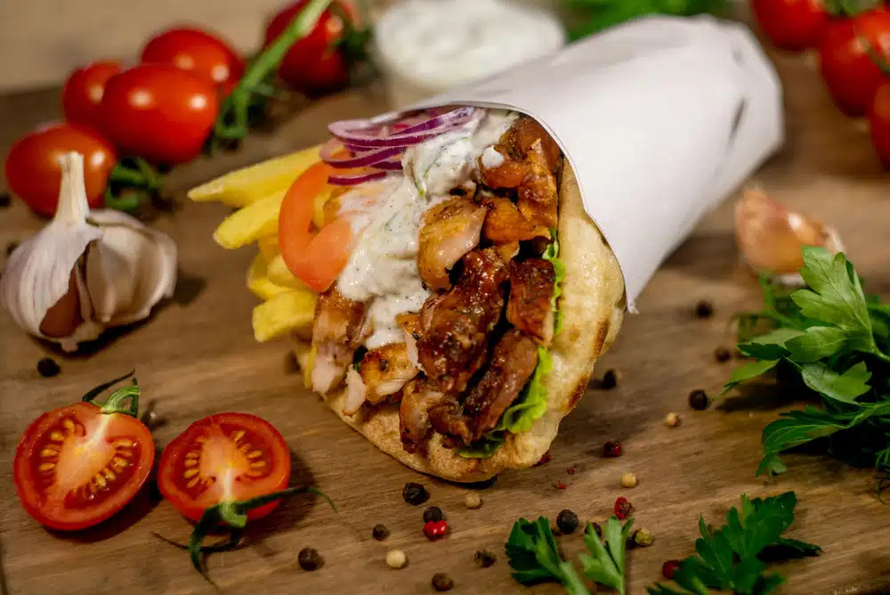 Gyros grego tradicional servido em pão pita com carne grelhada, molho tzatziki, tomate e cebola roxa, um clássico irresistível da culinária de Santorini.