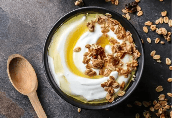 Iogurte grego tradicional servido com mel e granola, um dos sabores mais autênticos da culinária grega e do café da manhã mediterrâneo em Santorini.
