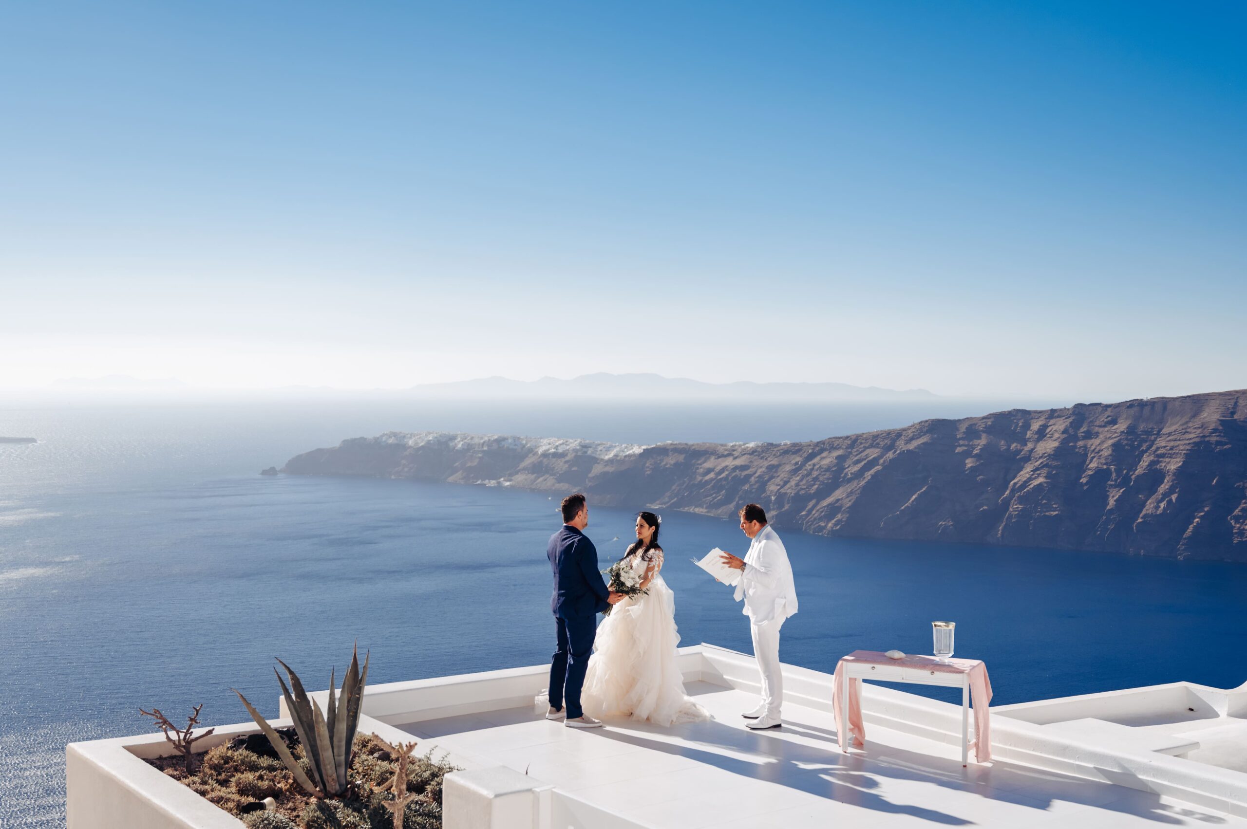 Casal e celebrante na caldeira em Santorini durante cerimonia casamento elopement