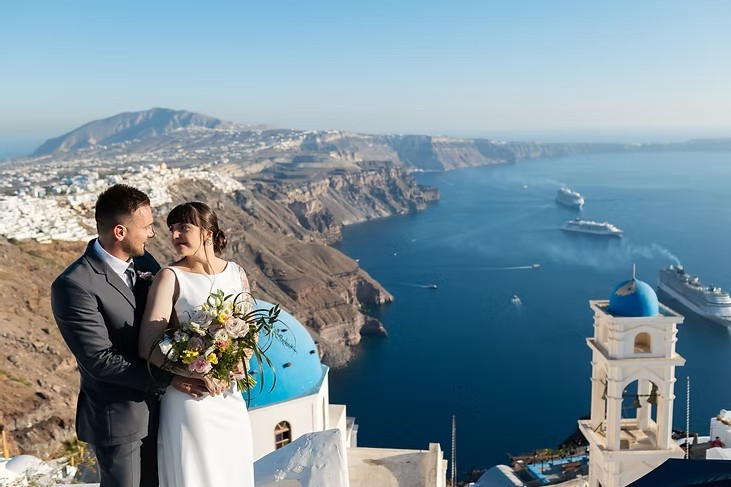Casal se olhando com a caldeira de Santorini ao fundo
