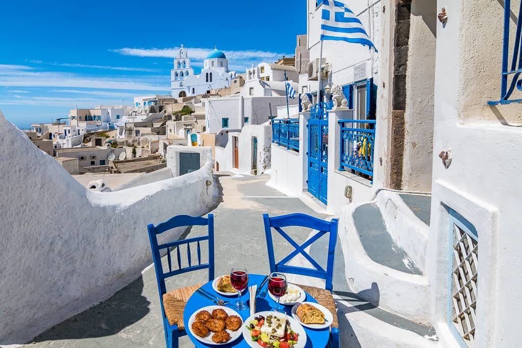 Culinária grega sendo exibida em uma mesa posta nas ruas de Santorini, Grécia