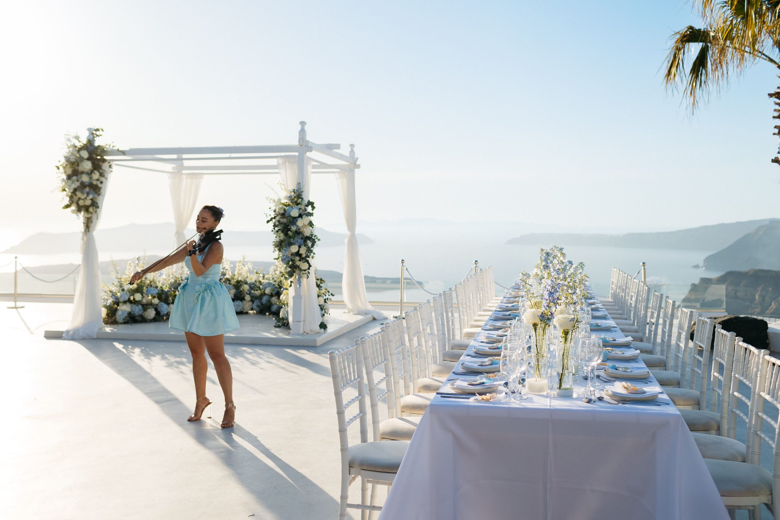 Violinista em terraço de cerimonia ao lado da mesa de jantar em Santorini, Grecia