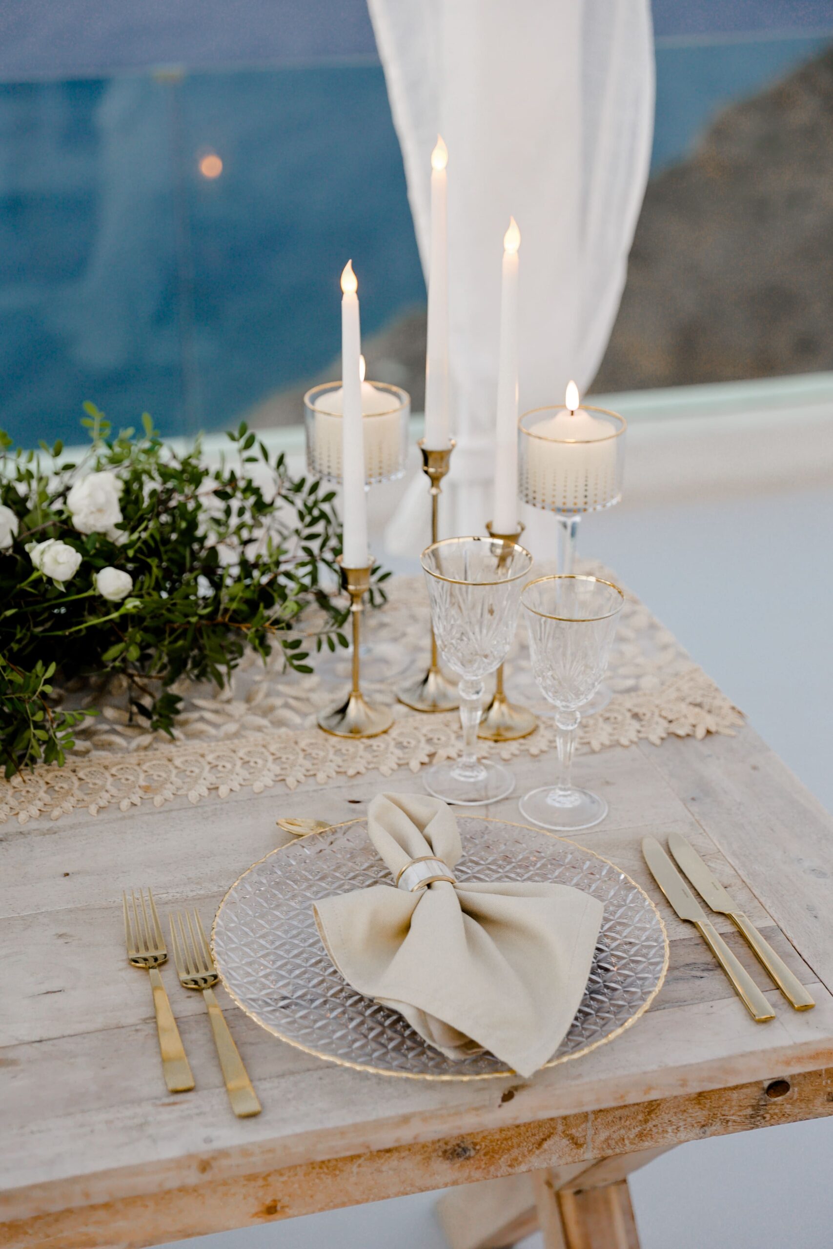 Mesa posta com velas, flores, prato, talheres, e guarda-napo, em Santorini, Grecia