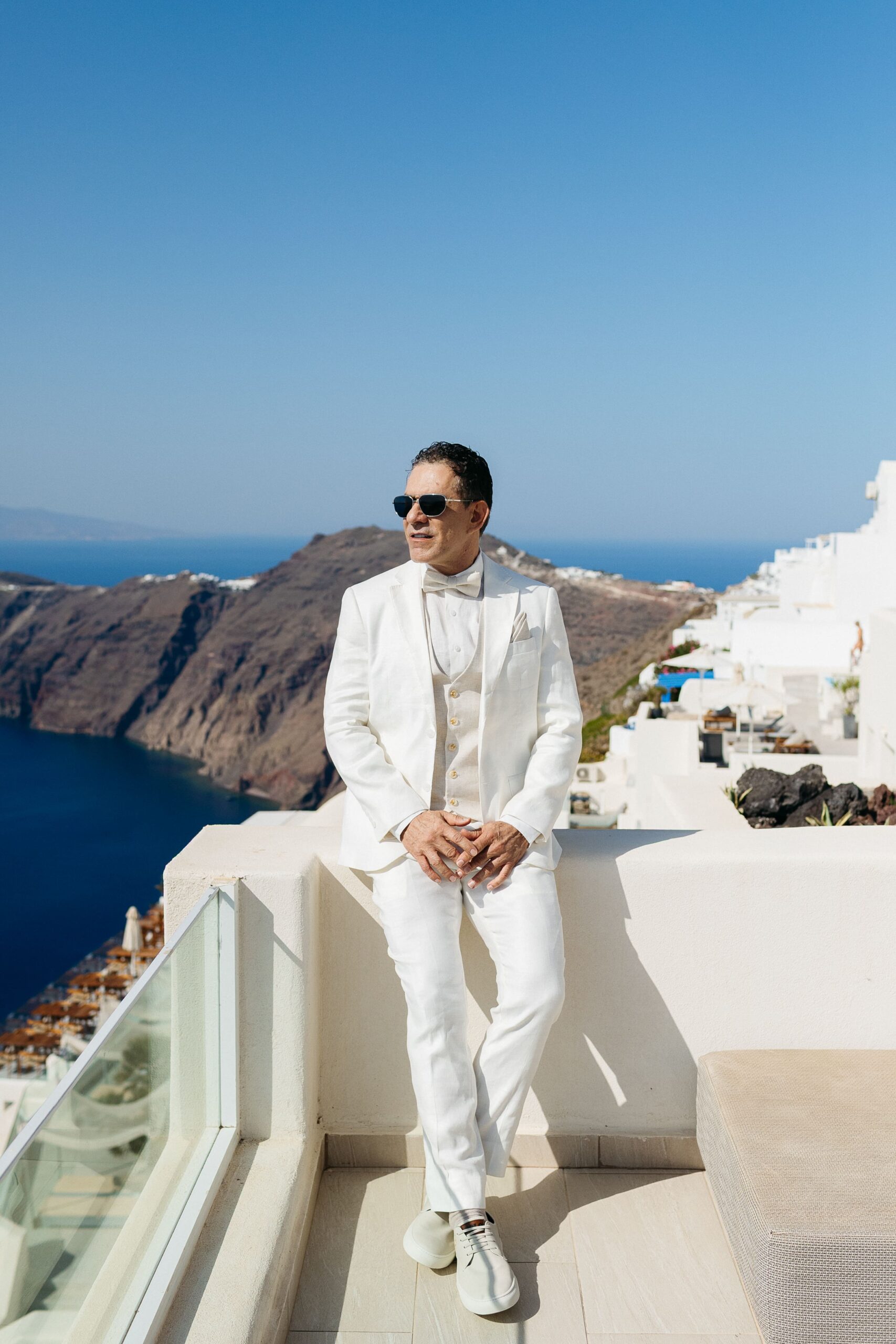 Noivo em terno branco em Santorini, Grecia