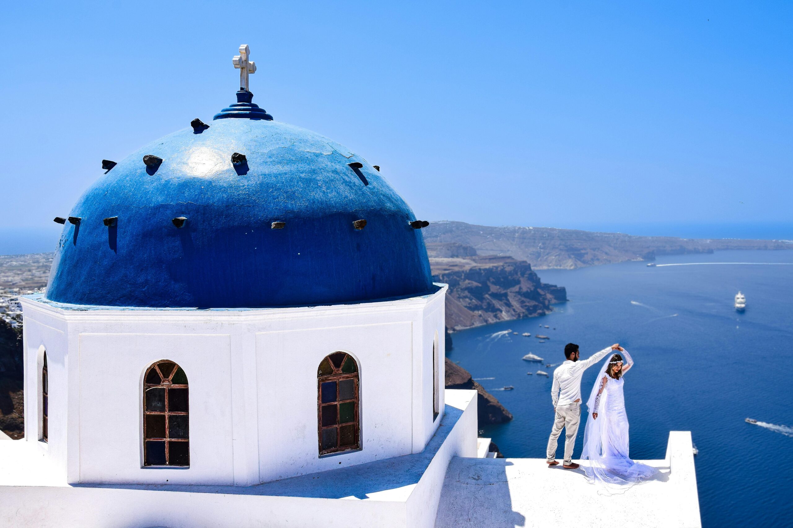 Noivos em frente a cupula azul em santorini grecia