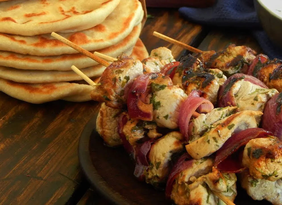 Souvlaki grego tradicional servido com pão pita, carne grelhada e cebola roxa, um dos pratos mais populares da culinária grega e de Santorini.